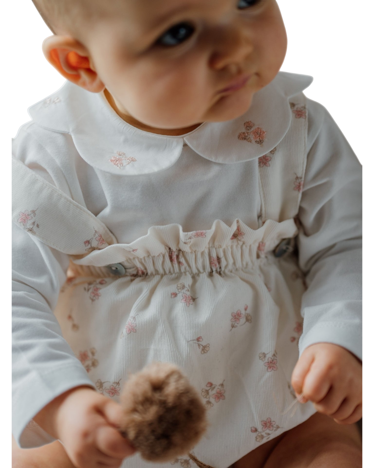 LilleLuxus baby wearing a white cotton long-sleeve body with a floral collar and ruffled waist detail